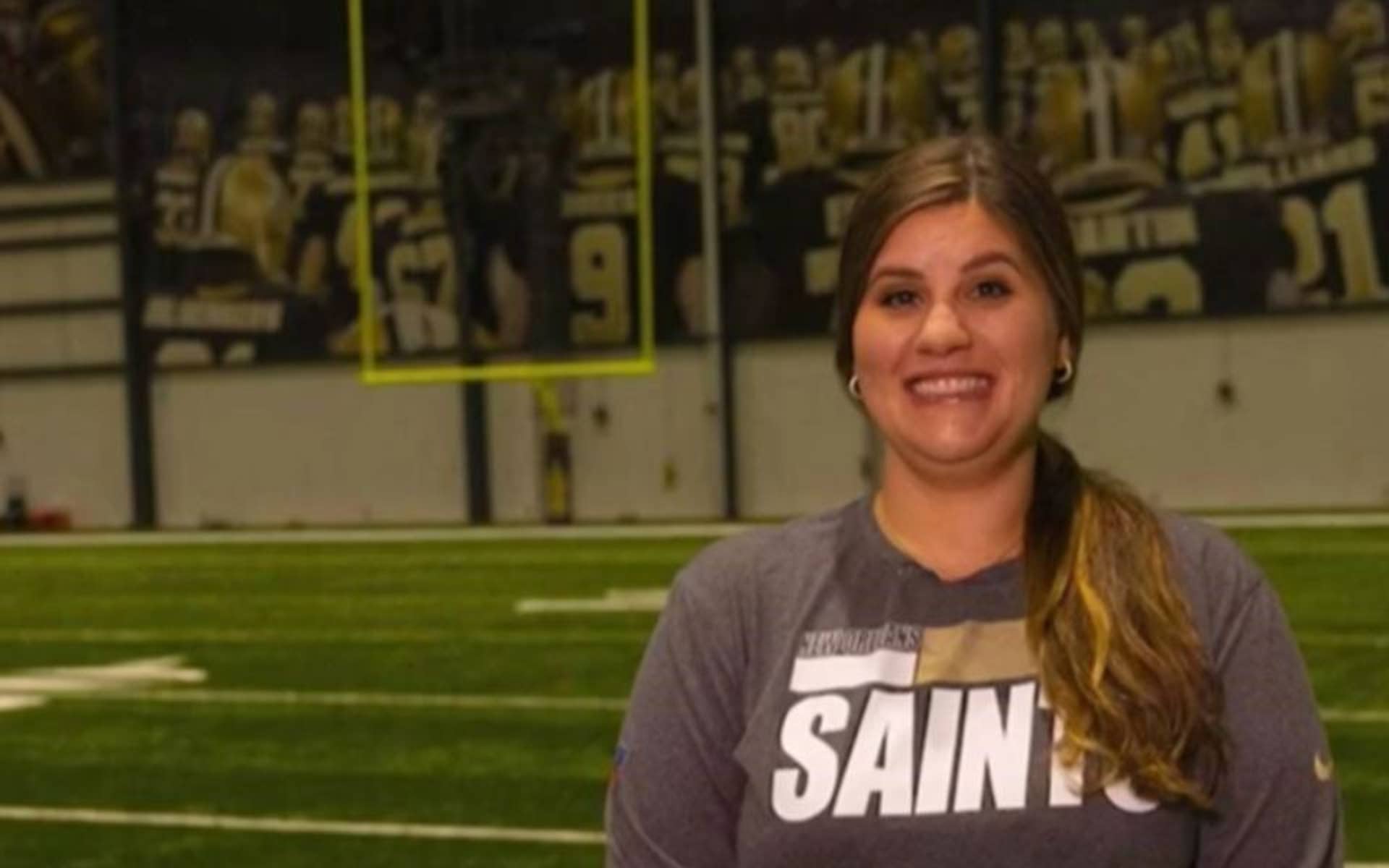 woman standing in an indoor football field smiling 