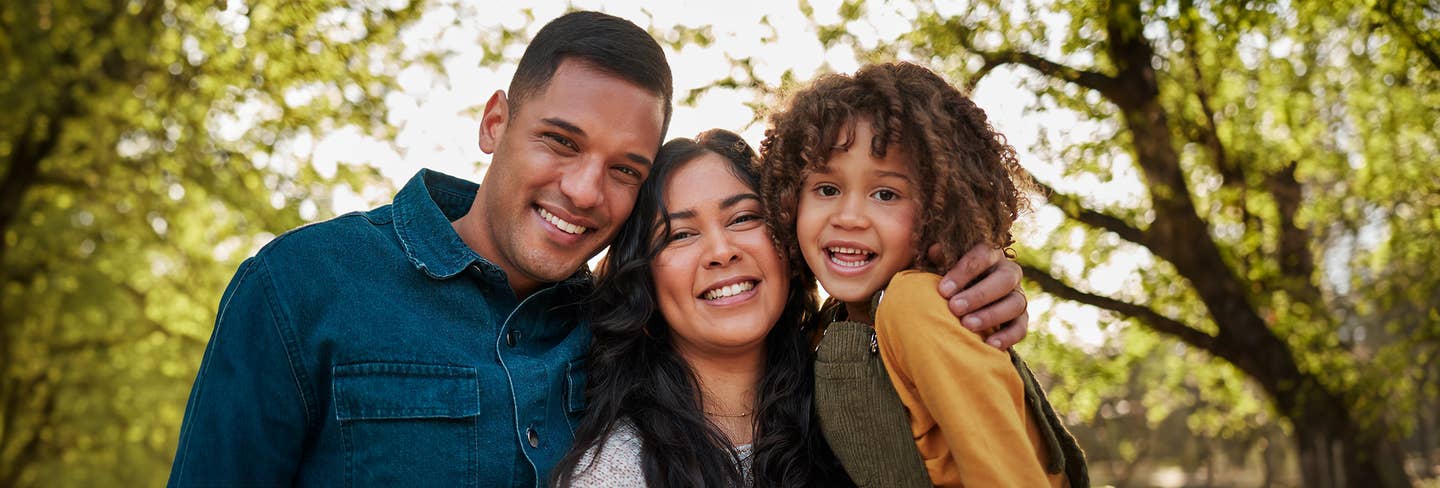 Family of three outside smiling