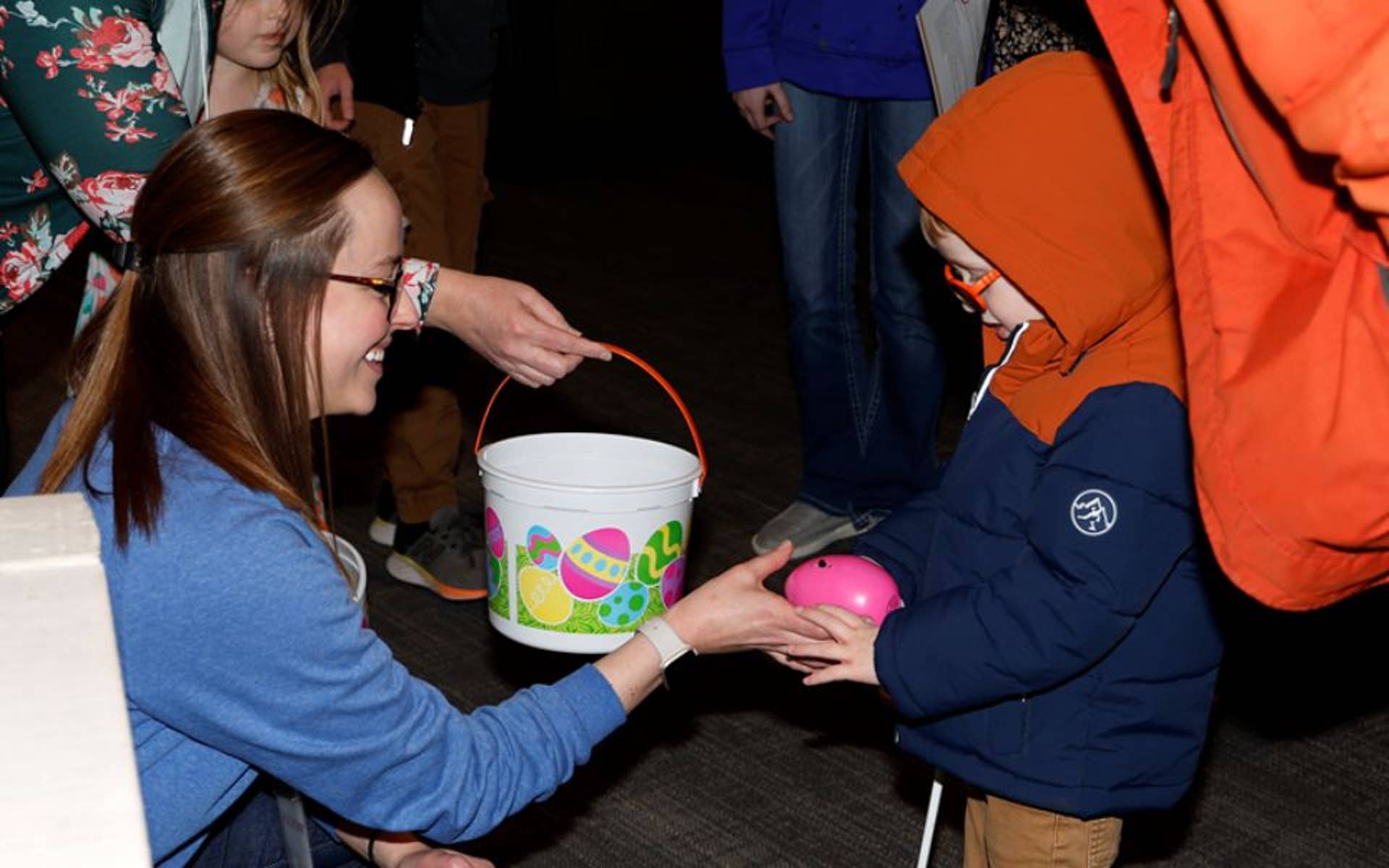 Young woman handing a young child an easter egg