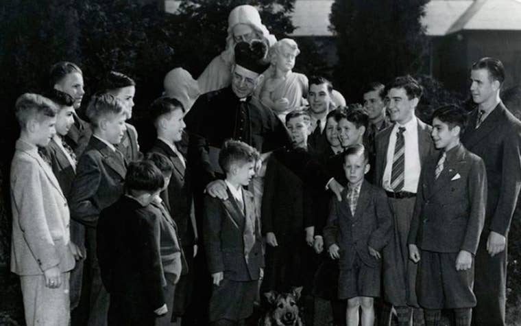 Black and white photo of Father Flangan surrounded by Boys Town Youth 