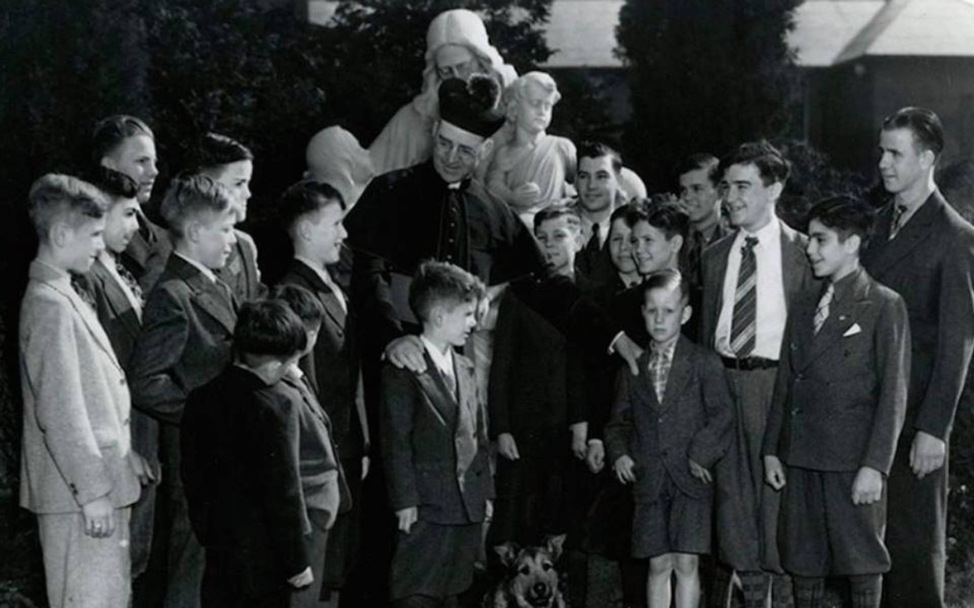 Black and white photo of Father Flangan surrounded by Boys Town Youth 