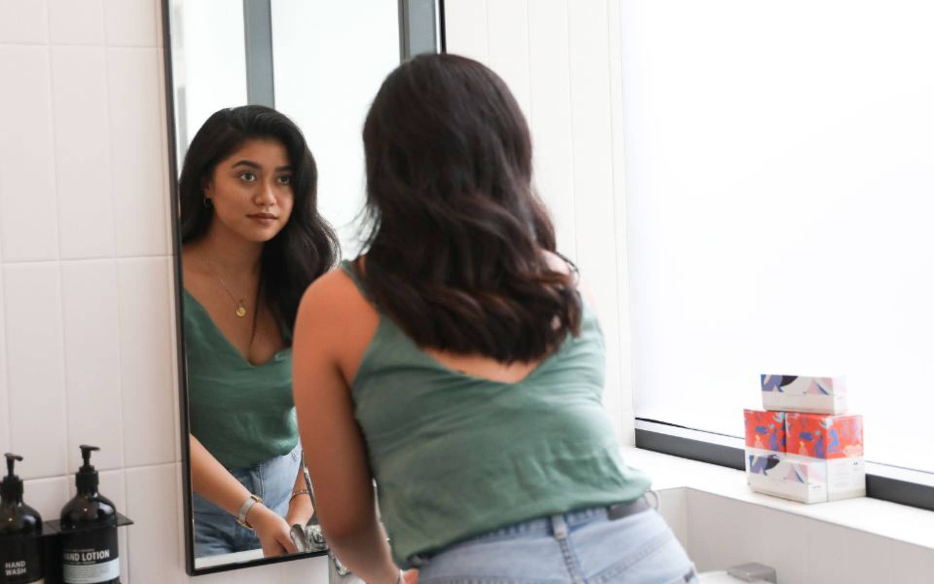 A young woman looking at herself in the mirror 