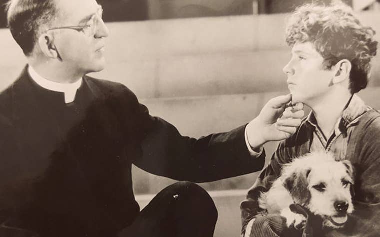 Father Flanagan talking to child holding a dog